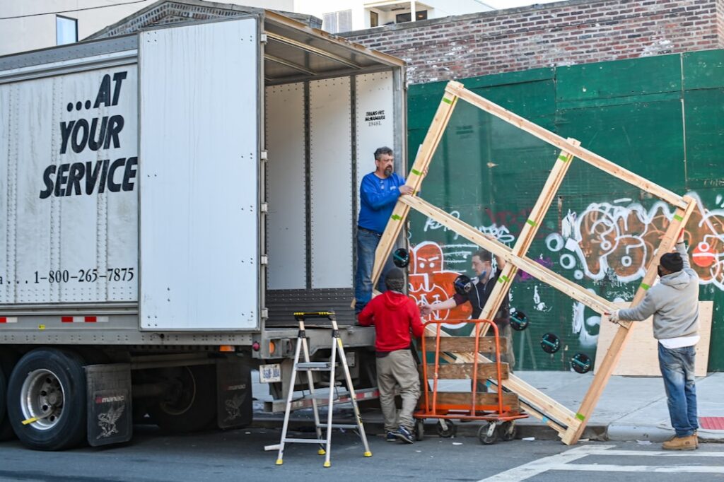 Professional movers loading large furniture and boxes onto a moving truck on a city street
