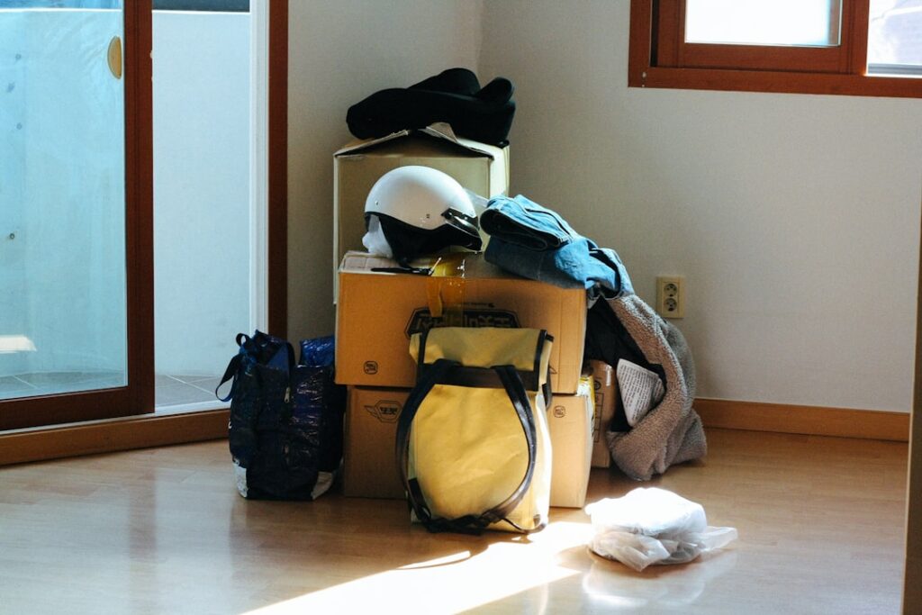 Boxes and bags piled in a bare, sunlit room ready for movers to collect, illustrating appliance and furniture prep before moving day.