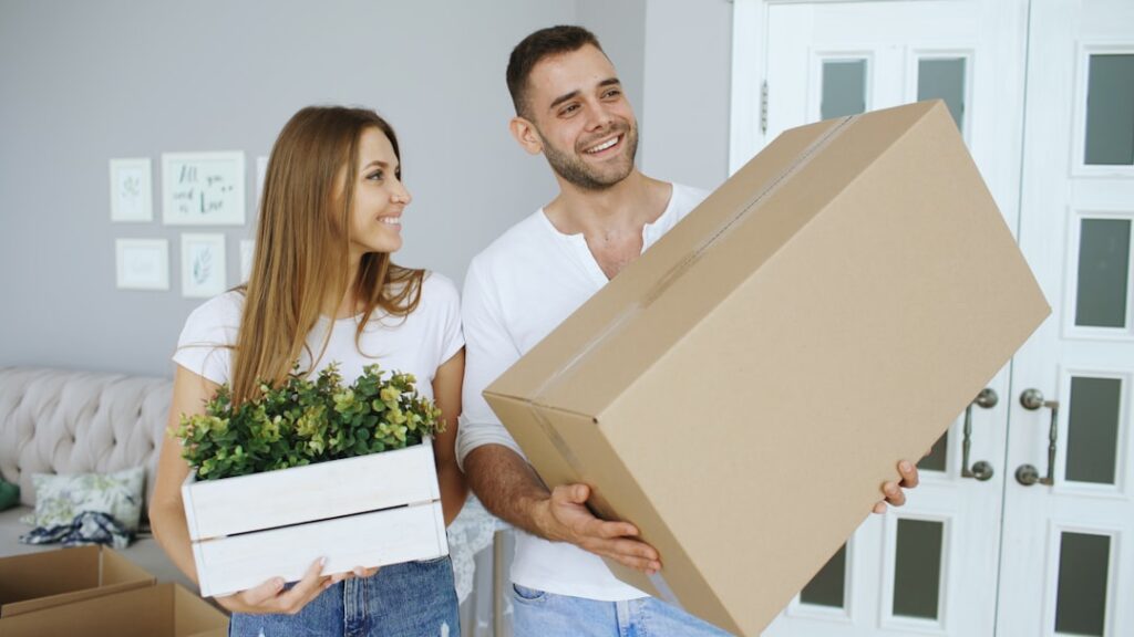 Happy couple carrying moving boxes into their new home on moving day